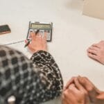 Dłonie przy umowie kupna i kalkulatorze podczas transakcji