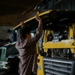 Mechanik w koszuli w kratę sprawdza silnik ciężarówki w warsztacie